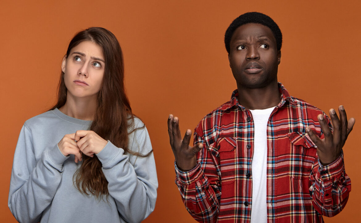 Frustrated black dark-skinned guy wearing red plaid shirt shrugg